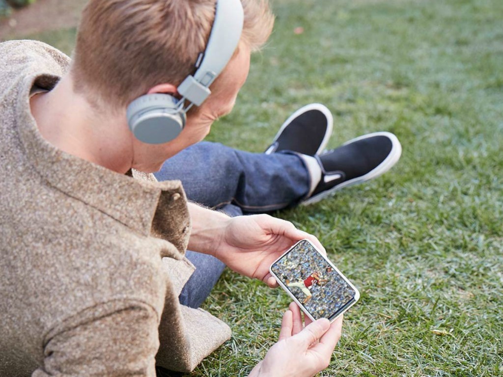 Man watching football on his phone with headphones