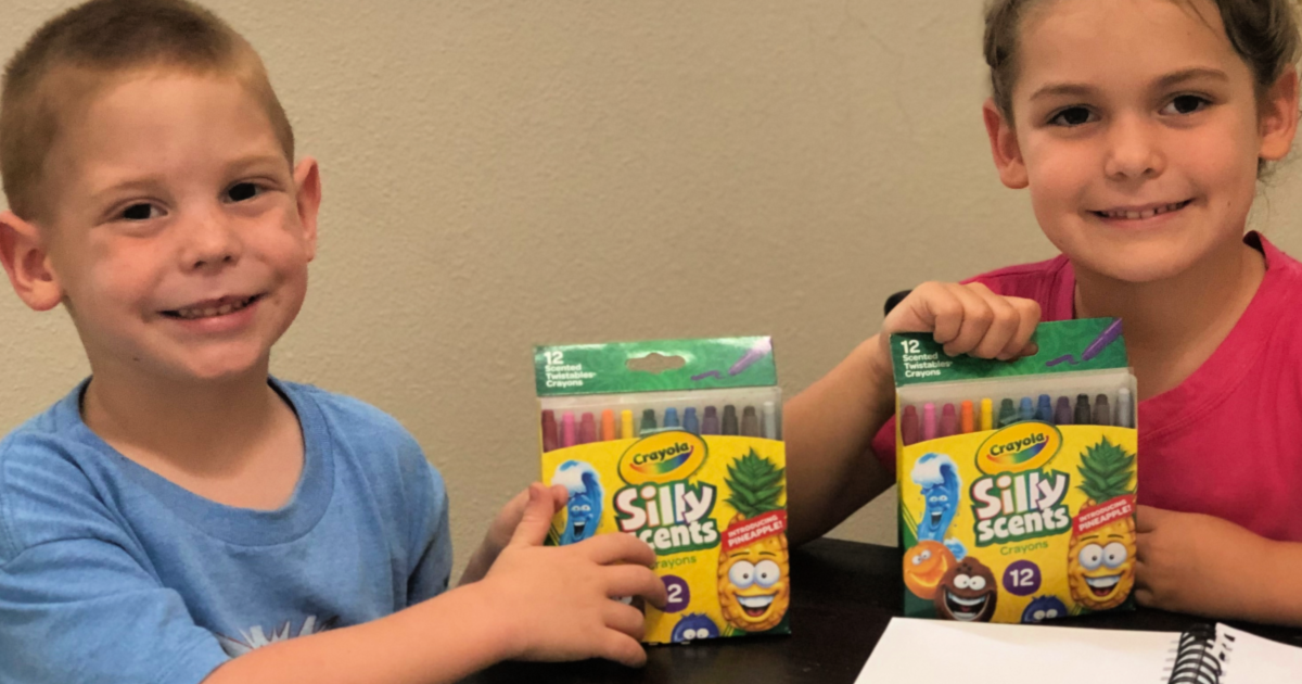 Crayola Silly Scents Twistable Crayons being held by boy and girl and notebook on table