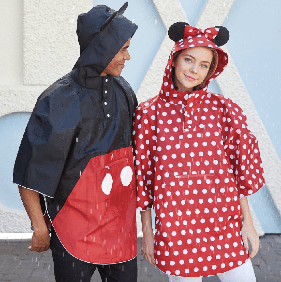 Man & woman wearing Dinsey Rain Ponchos in the rain