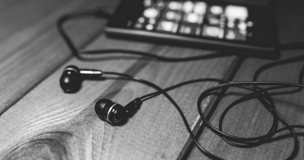 black earbuds attached to iphone laying on table