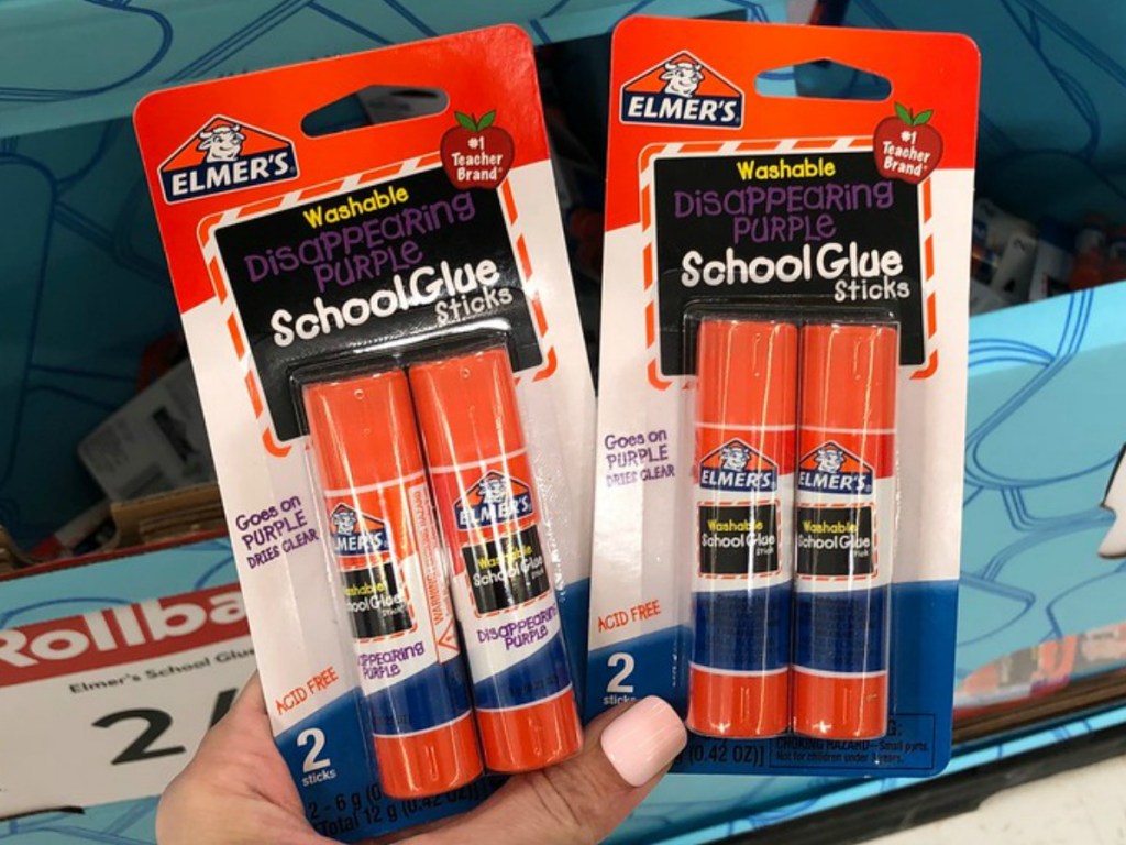 hand holding packages of glue sticks by store display