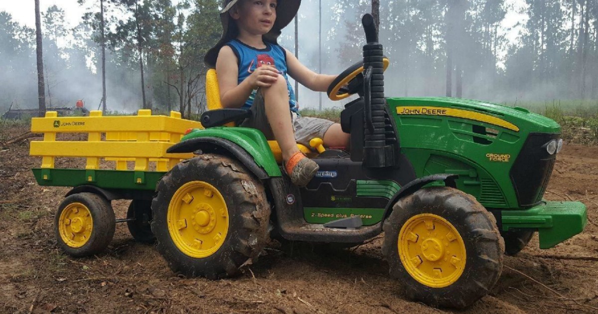 boy riding John Deere Peg Perego Tractor in woods