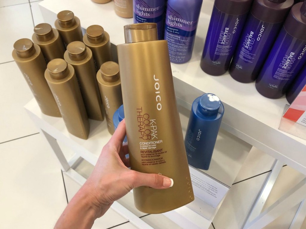 lady holding Joico shampoo at the store