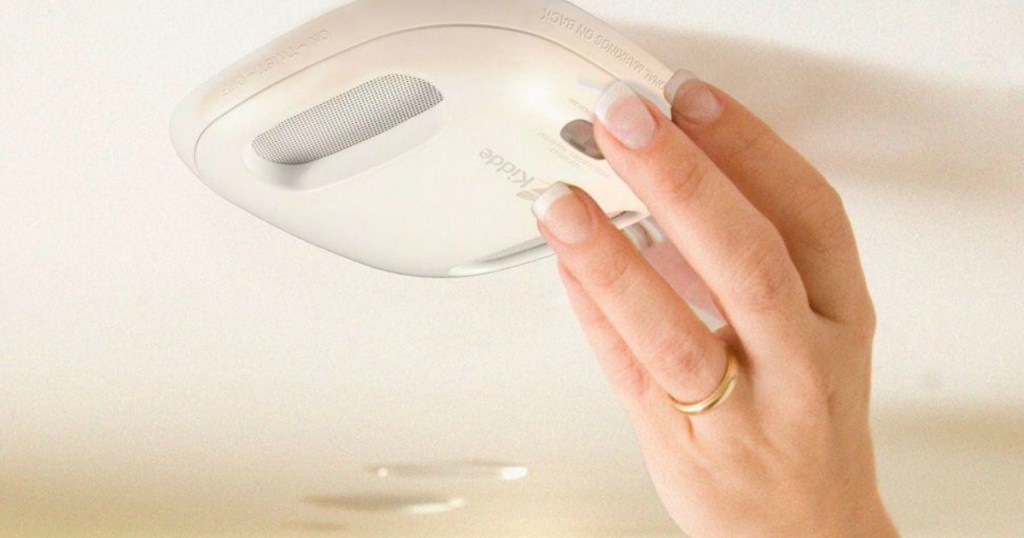 woman adjusting smoke alarm