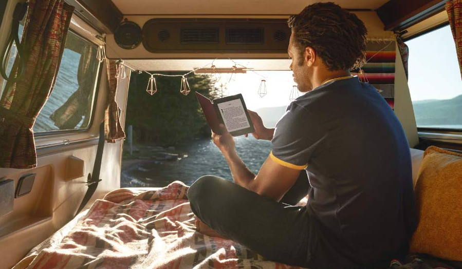 man holding Kindle eReader in camping trailer