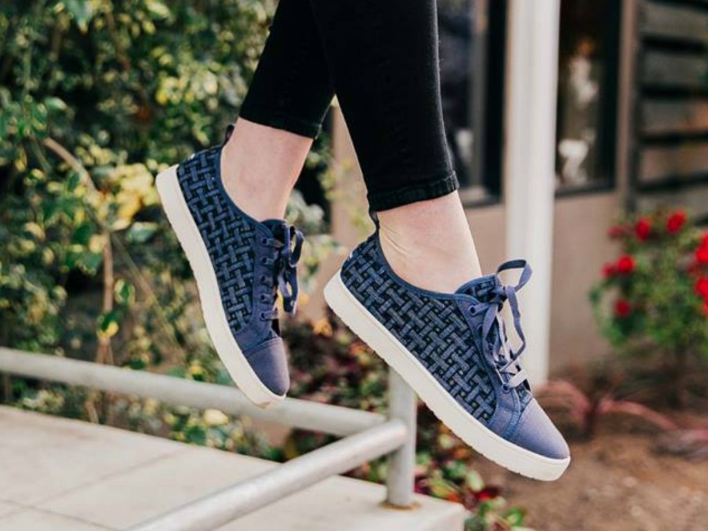 women's legs dangling with blue denim shoes