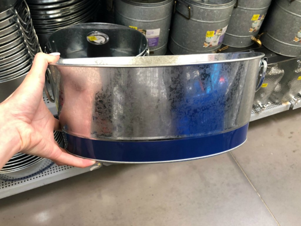 hand holding silver and blue bucket