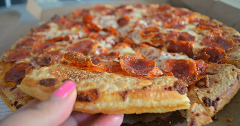 Woman's hand grabbing a piece of pepperoni pizza