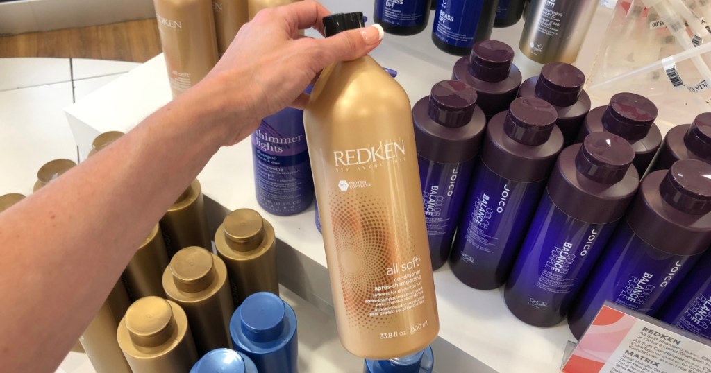 hand holding redken all soft shampoo