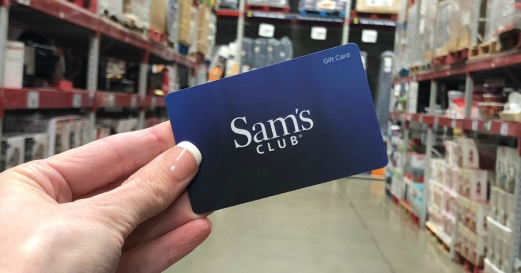 Hand holding Sam's Club gift card in store