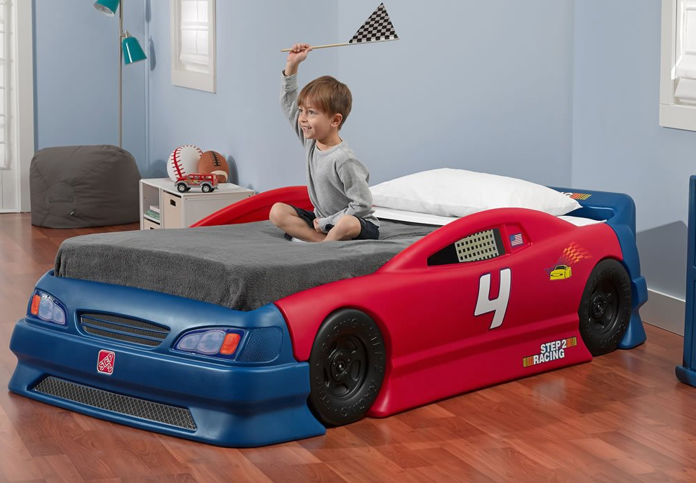 Toddler boy sitting on Step2 Stock Car Convertible Bed