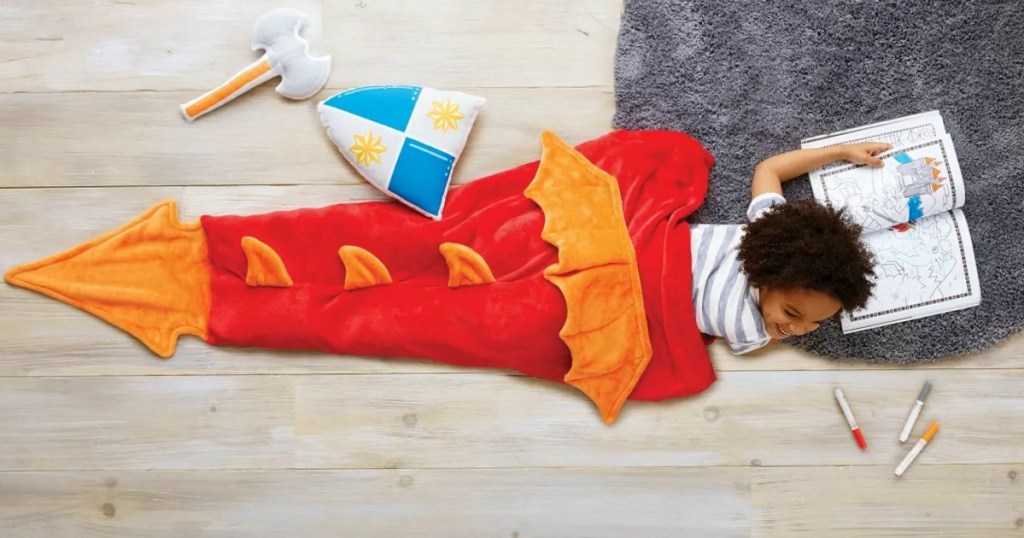 Boy laying on grey fur rug with dragon tail wearable blanket