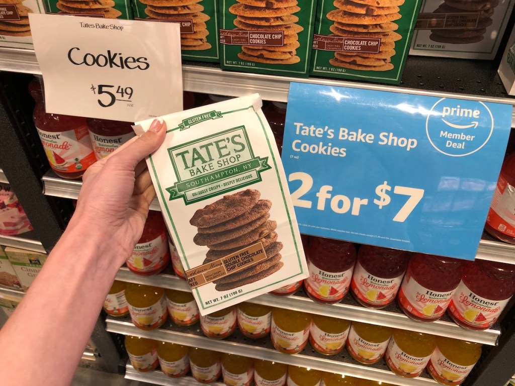 hand holding whole foods tate bake shop cookies in front of sale sign at whole foods