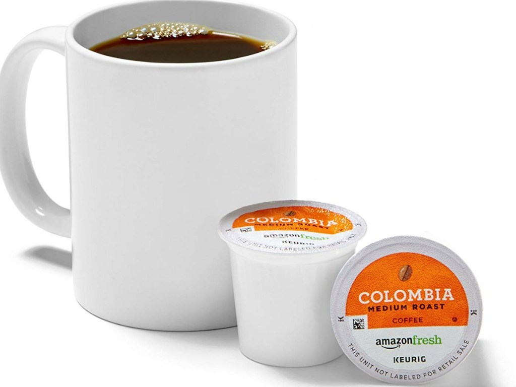 cup of coffee sitting next to two coffee pods