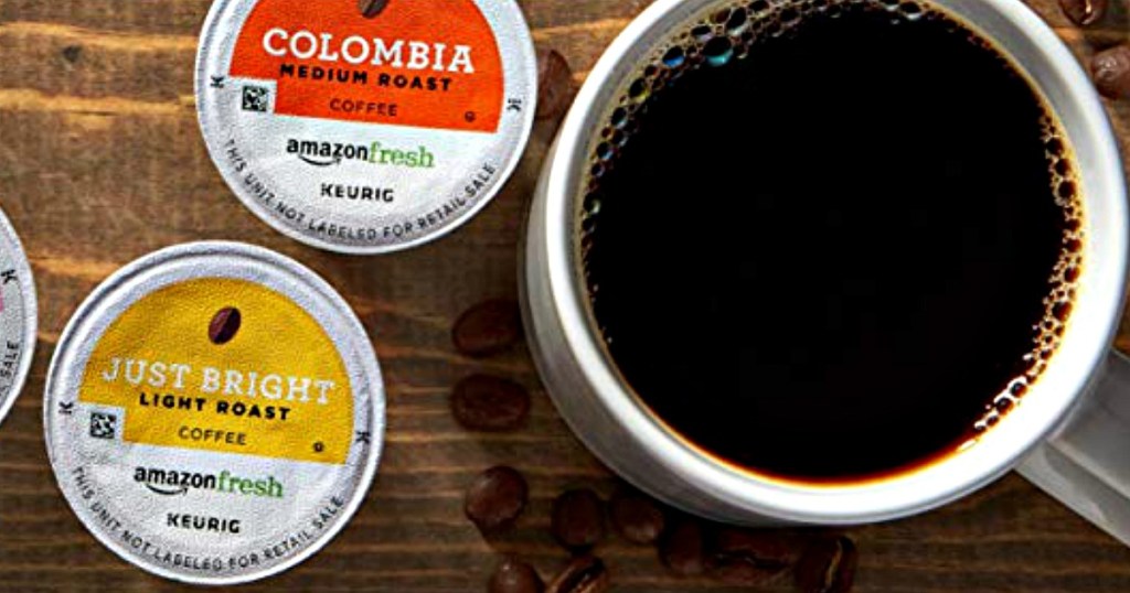 cup of coffee sitting on a table near coffee pods