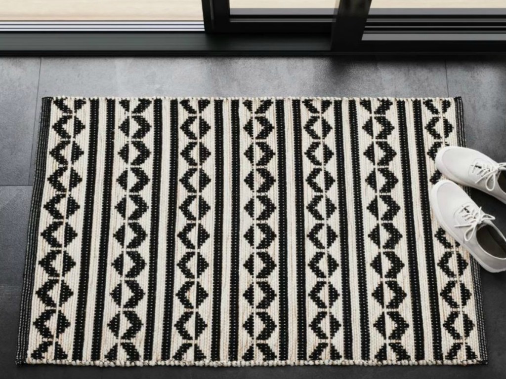 black and white rug by door with a pair of shoes next to it
