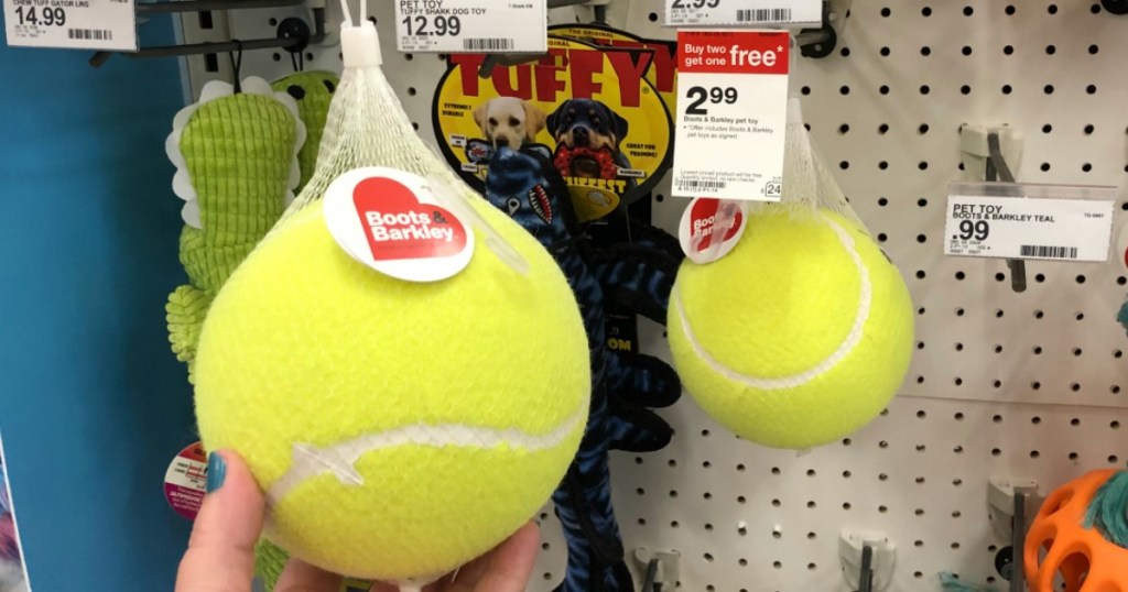 hand holding large yellow tennis ball by store display