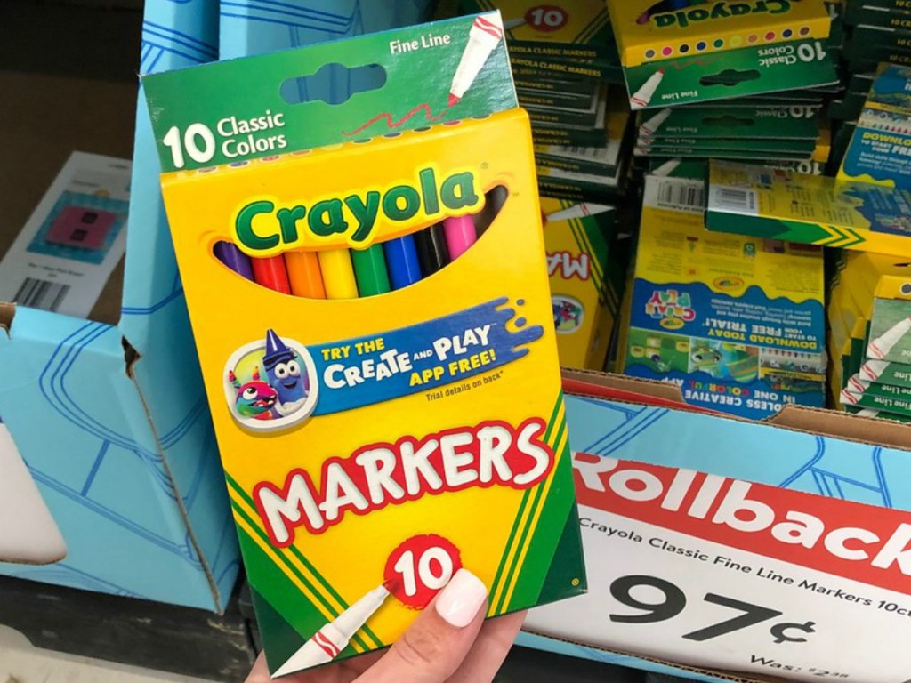 hand holding package of markers by store sign