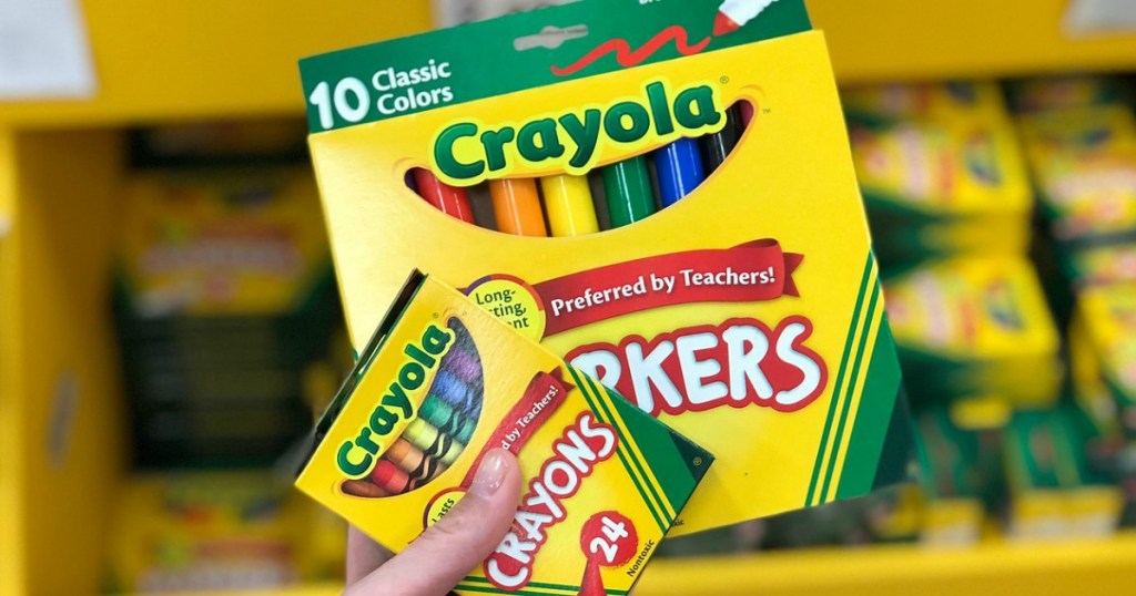 hand holding up crayons and markers
