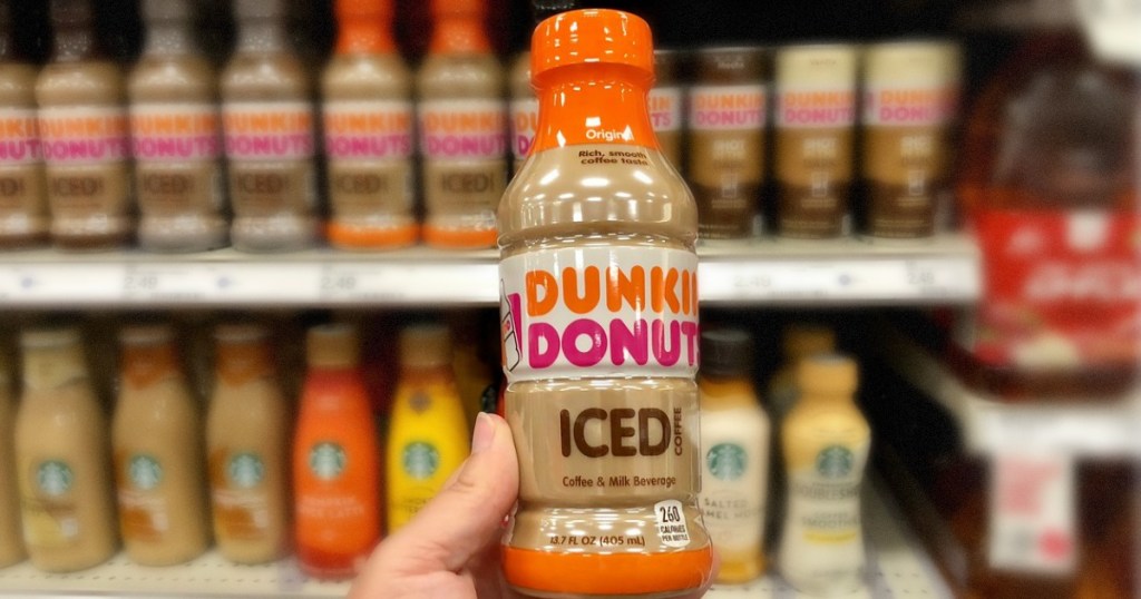 hand holding bottle of iced coffee in front of store display