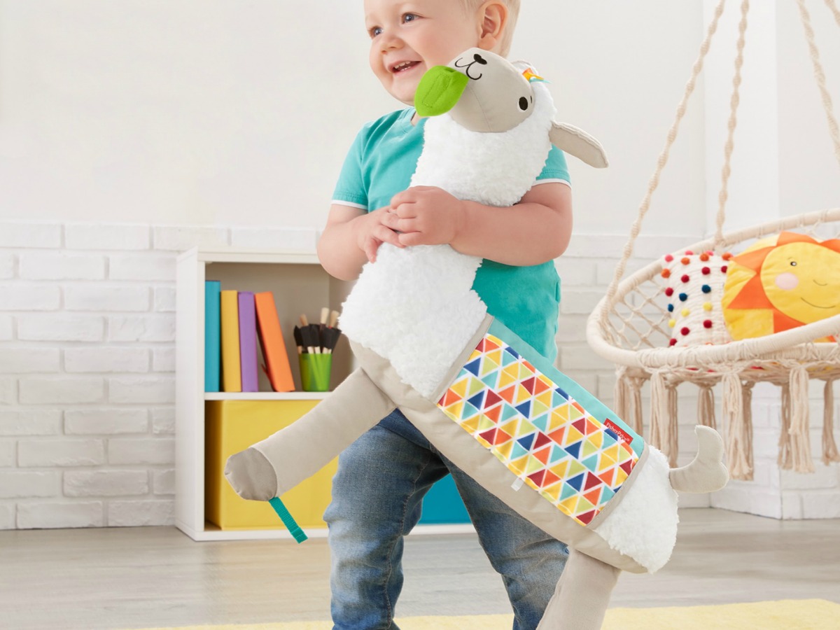 toddler boy walking around room holding plush toy