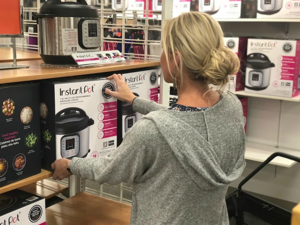 woman in store taking pressure cooker off shelf