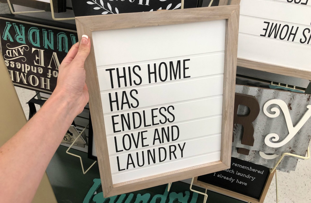 white wooden this home has endless love and laundry sign being held in store
