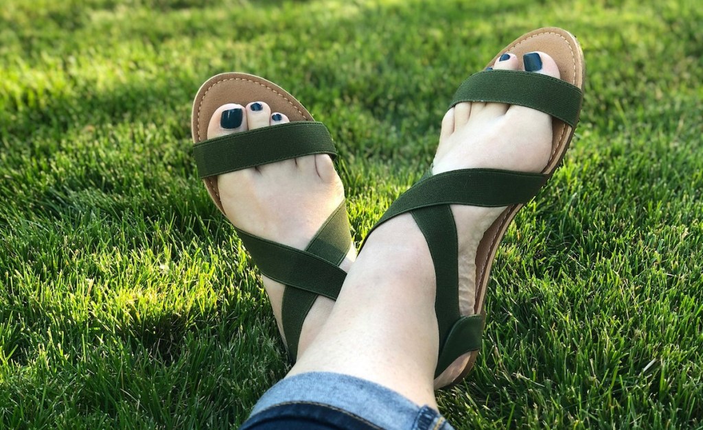 feet wearing dark green sandals in grass