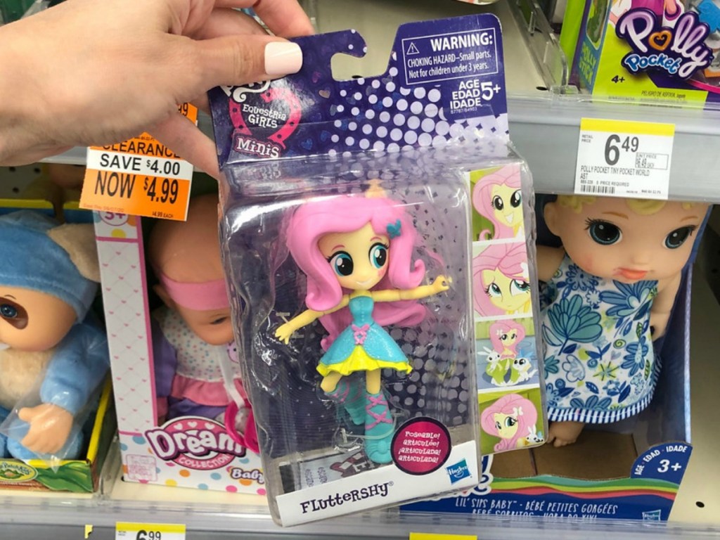 hand holding toy in package with pink doll at store