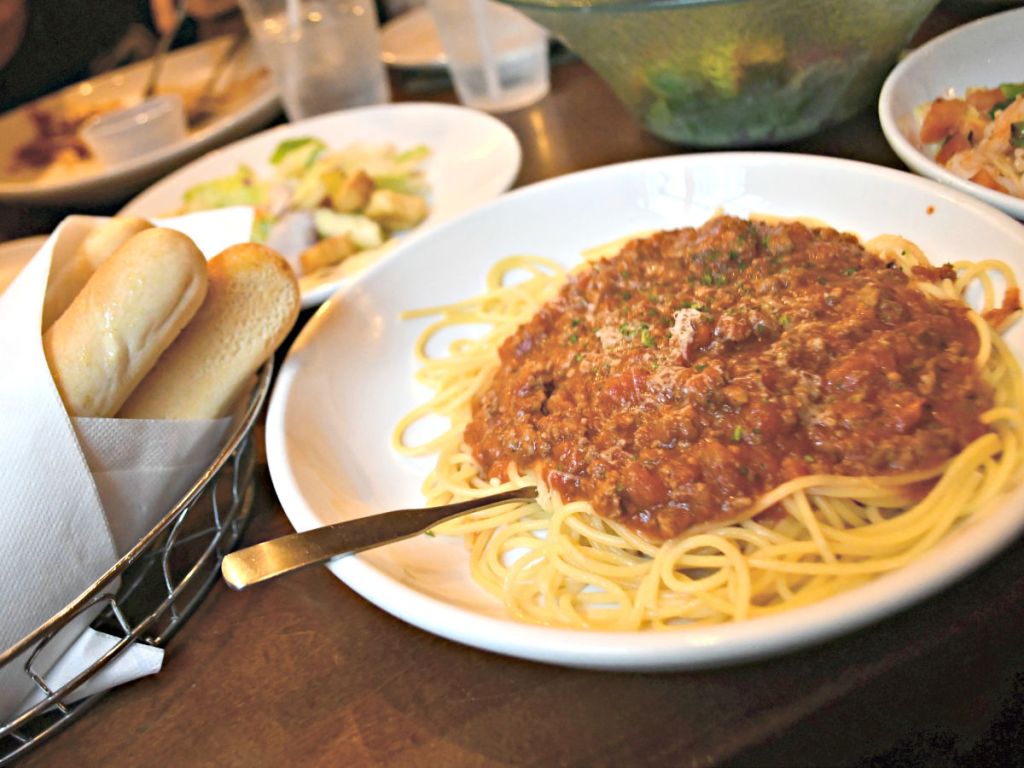 olive garden meat sauce pasta at table with bread and salad