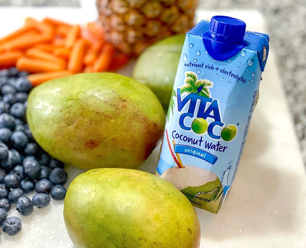 mangos and coconut water on counter with blueberries and carrots