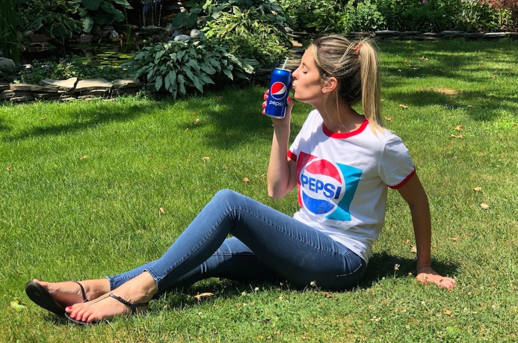 woman wearing pepsi shirt with soda in grass