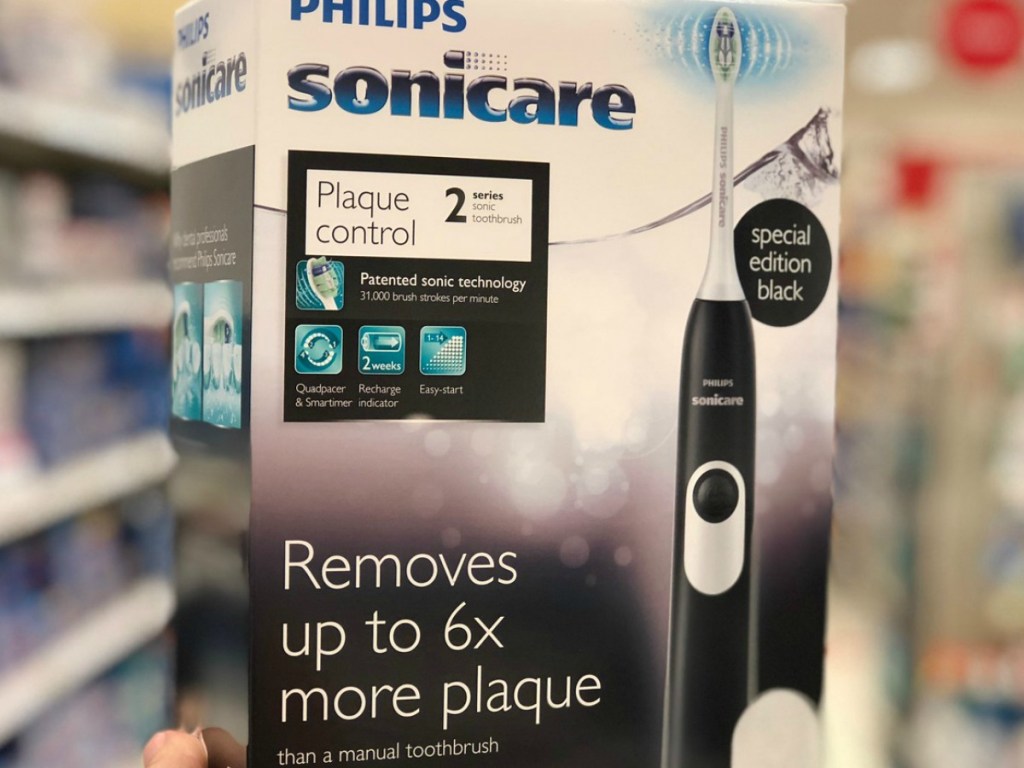 someone holding a box with a black toothbrush in the store