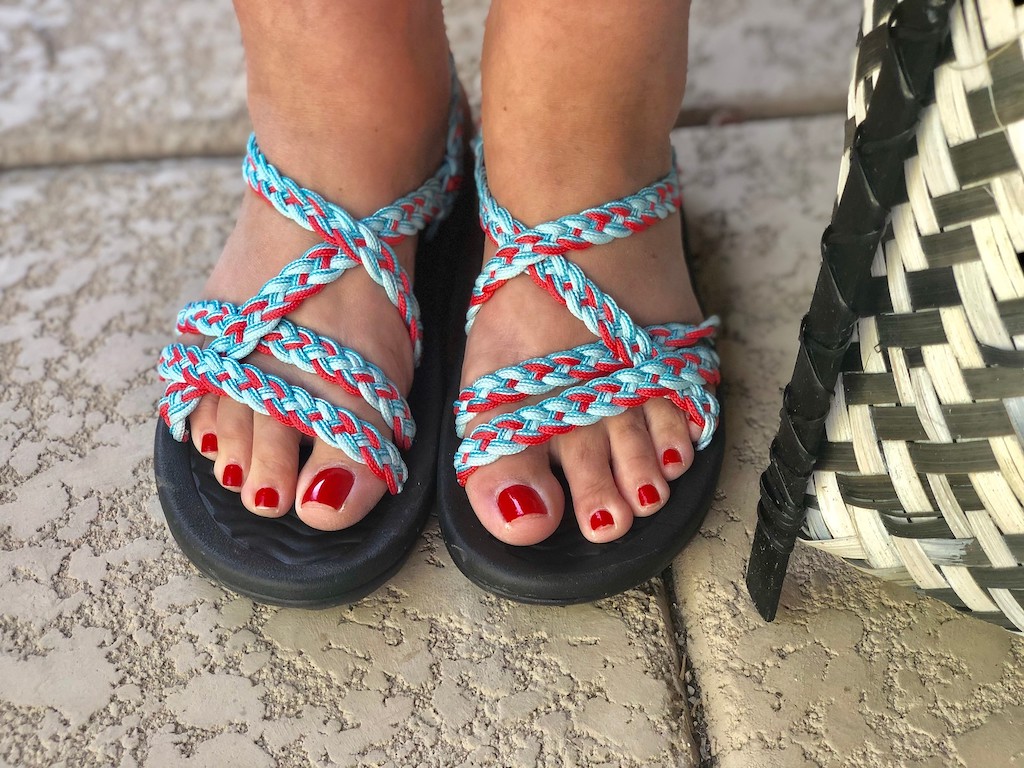 feet in strappy sandals with painted red toenails 