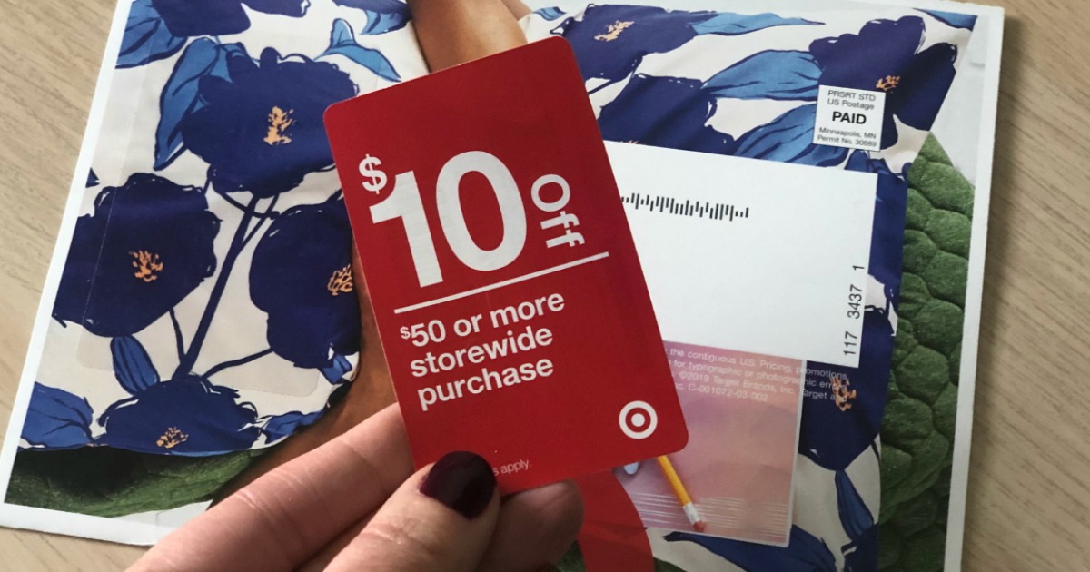hand holding red coupon by mail on table