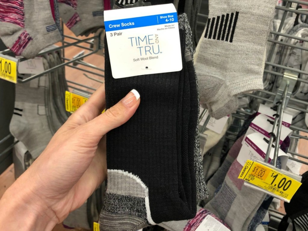 hand holding black pair of socks by store display