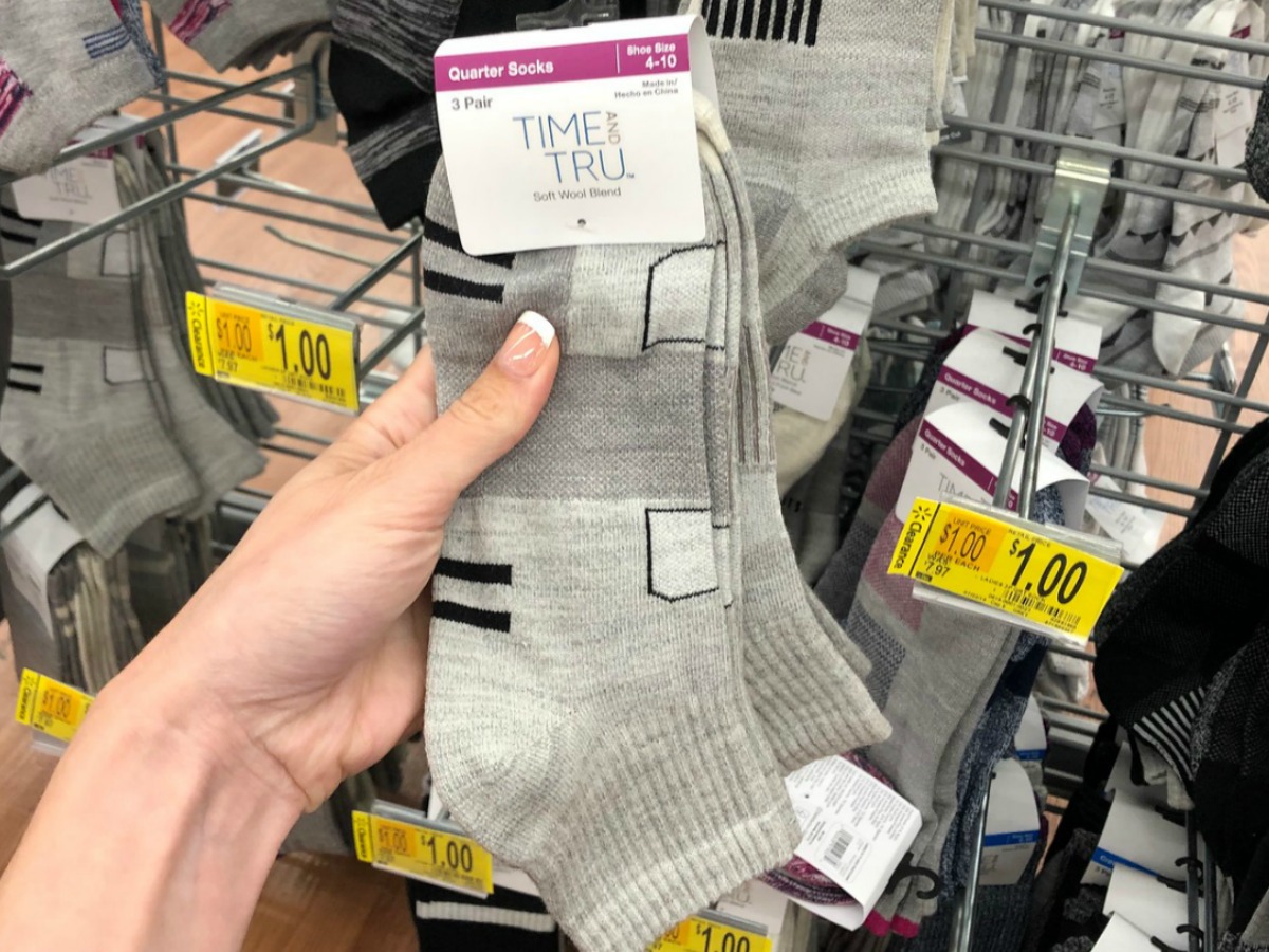 hand holding grey pair of socks by store display