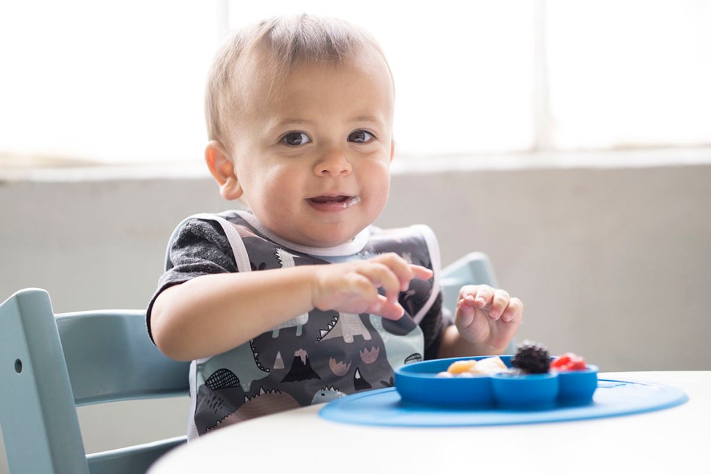 toddler eating from sesame street ezpz mat