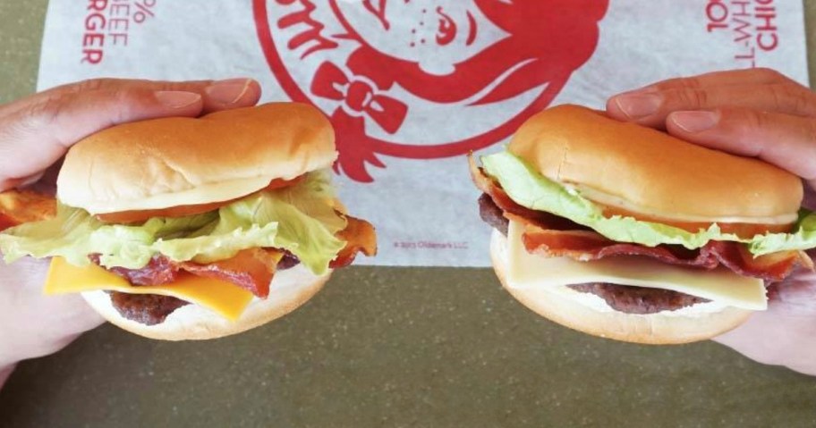 two hands holding wendy's Jr. Bacon Cheeseburger