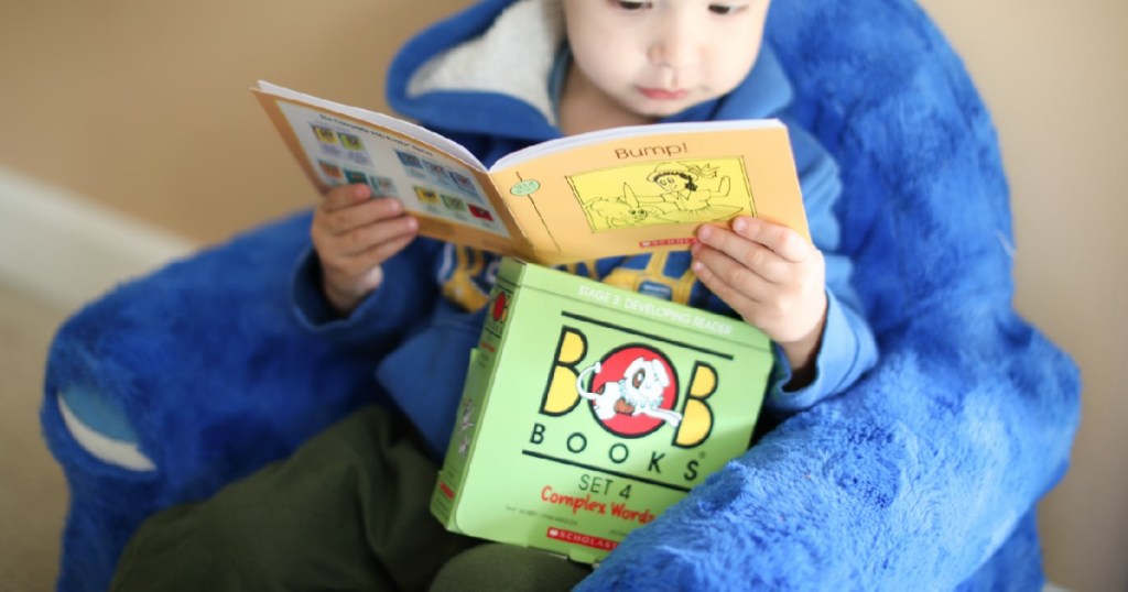 Child reading BOB books set in blue shark chair