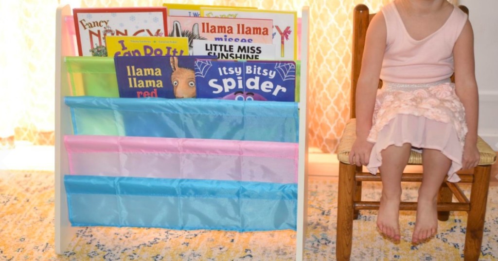 little girl sitting in a chair next to a book shelf