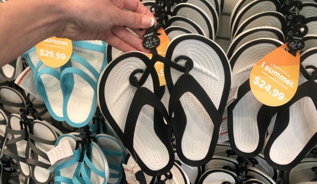 Crocs Flip Flops in black and white in hand on hanger in store