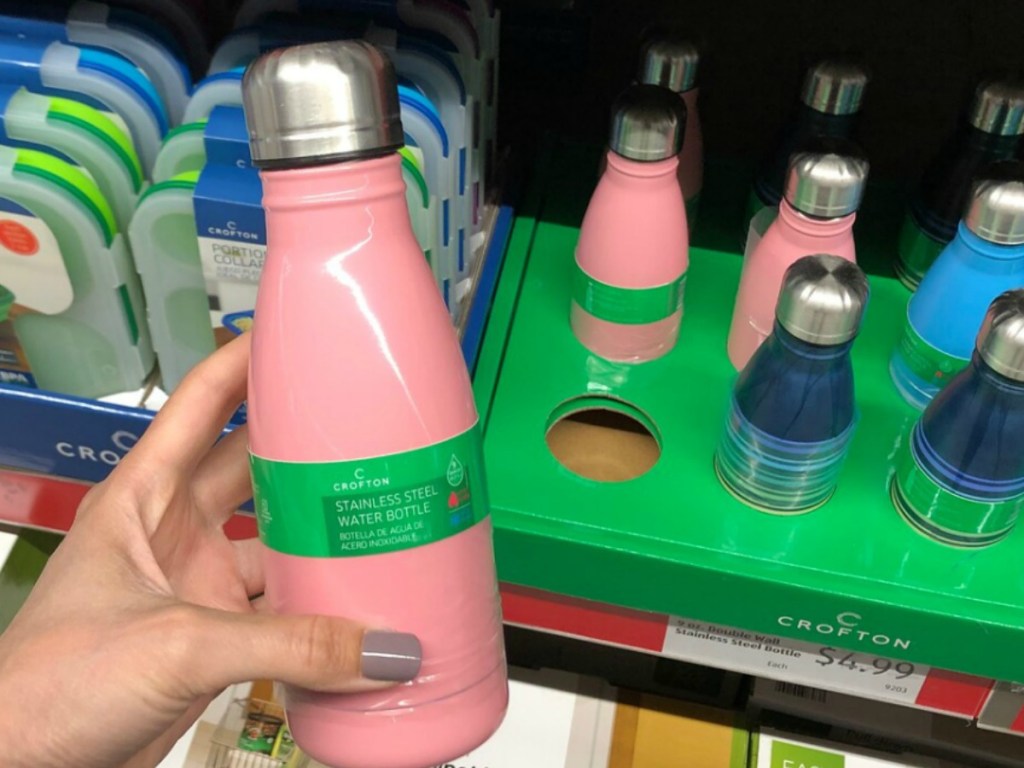 hand holding pink water bottle near store display