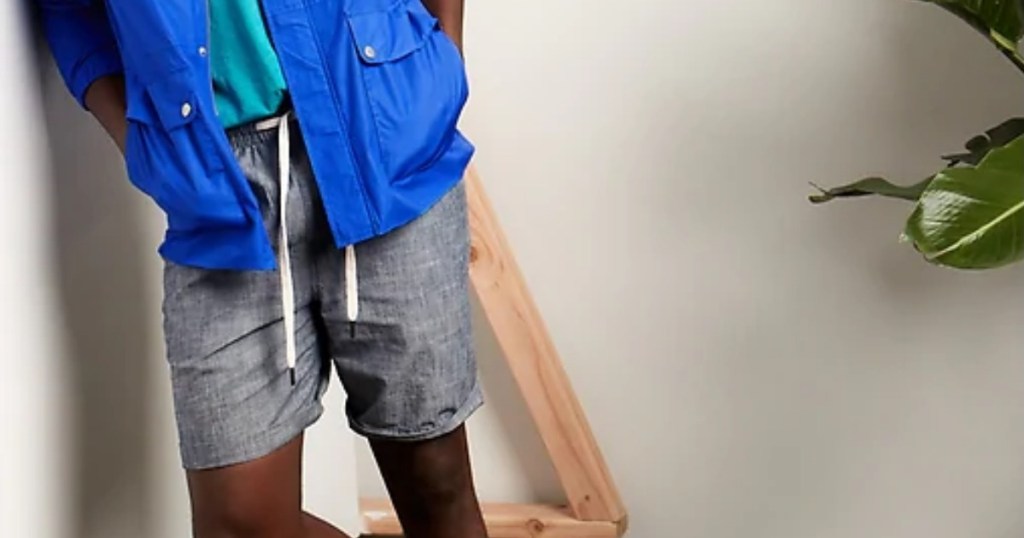 man leaning against wall wearing deck shorts