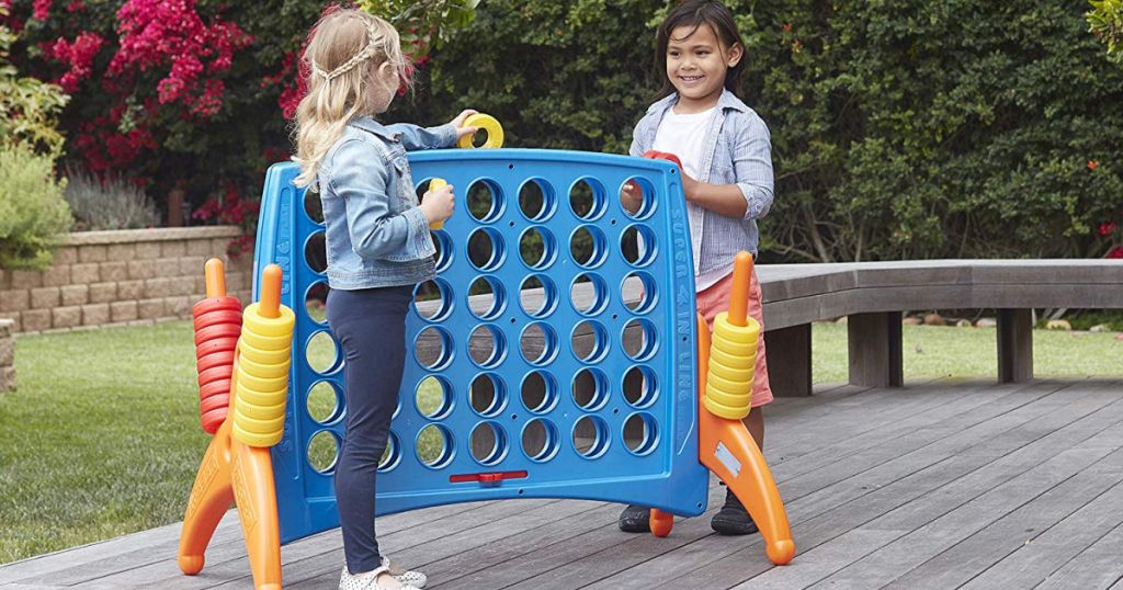 two kids playing with ECR4Kids Junior 4-to-Score Giant Game Set on backyard patio