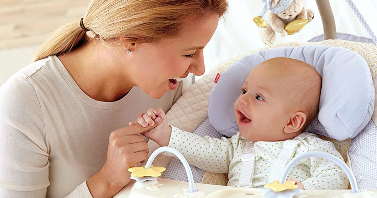 mother sitting next to a baby in a swing