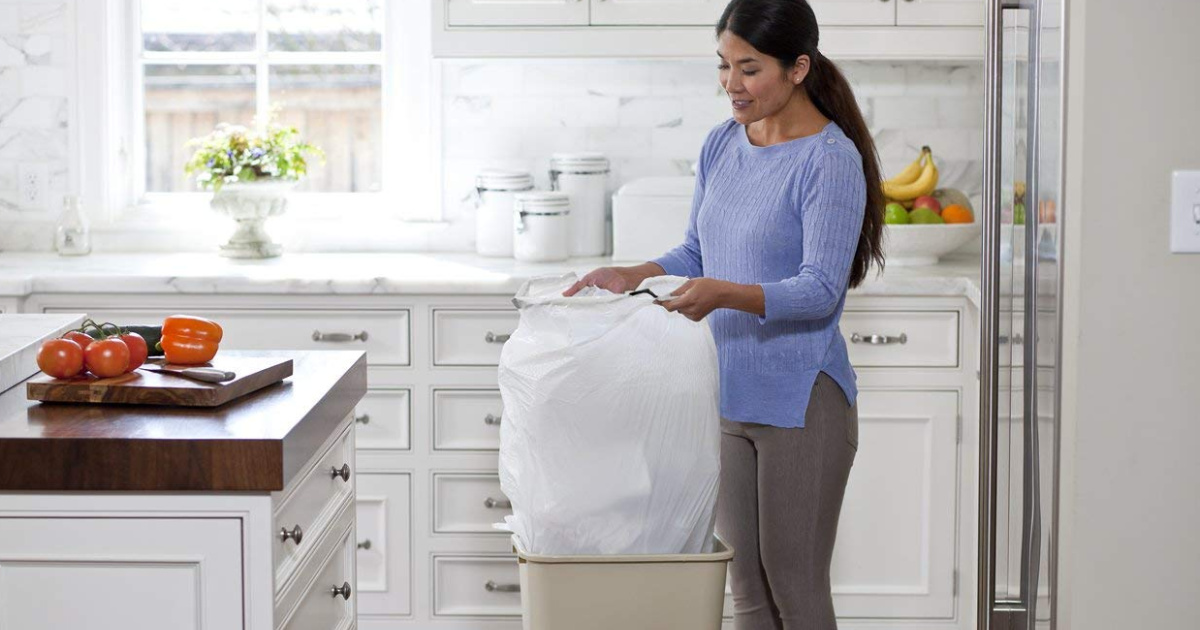 Woman holding white Trash Bag in kitchen