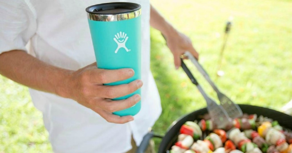 man holding a Hydro Flask and grilling outdoors