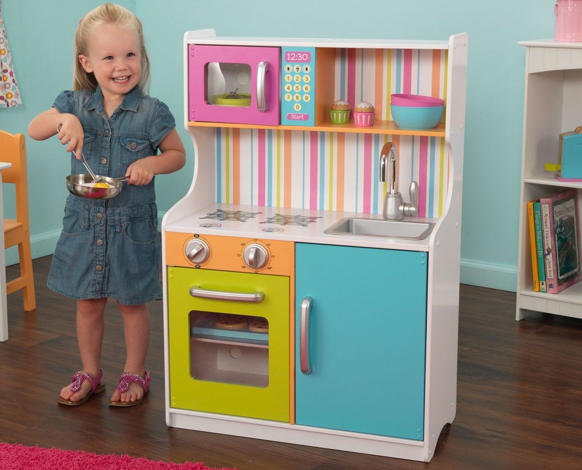 child next to toy kitchen