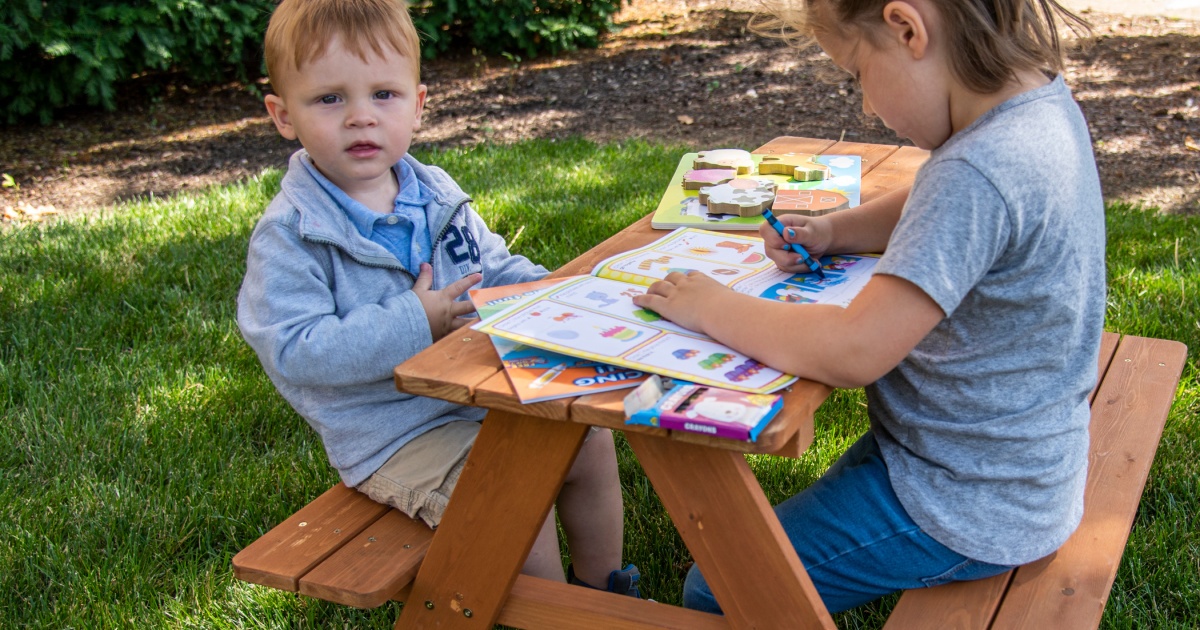 kids sitting at picnic table with books